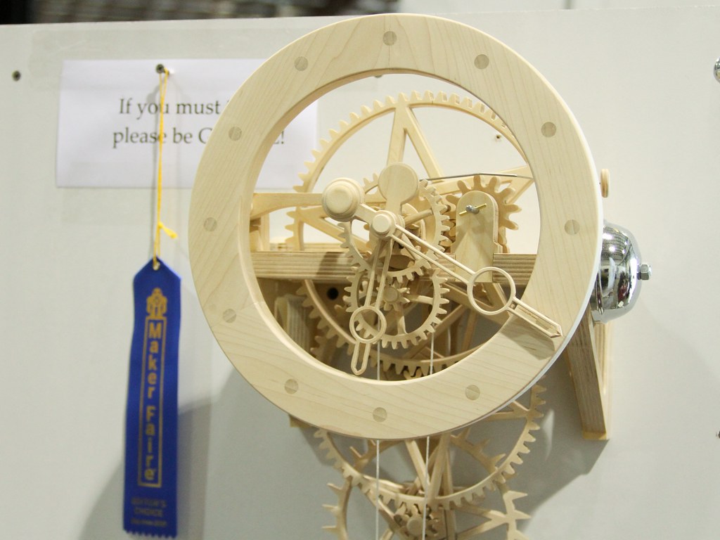 Figure 3 — 3 — A finished wooden moving-gear clock: a laser-cut plywood gear train with the whole movement on show — the kind of buildable kit or plan (Clayton Boyer-style) the gear-train thread is s…